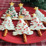 Covrigei de Crăciun în formă de brăduți, aranjați pe o farfurie roșie festivă.
