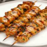 Frigărui de pui la airfryer rumenite, glazurate și presărate cu verdeață, servite pe farfurie albă