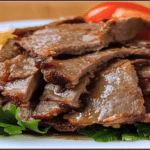 Felii suculente de carne pentru viral doner kebab, așezate pe verdeață, gata de servit pe farfurie.