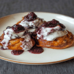 Papanasi la airfryer – cea mai practică rețetă pentru acasă 6 Papanasi la airfryer serviți pe farfurie, cu sos de afine și smântână, văzuți din față