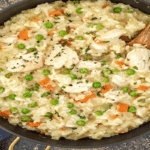 Pilaf de orez cu pui cremos, mazăre și morcovi, văzut de sus într-o tigaie