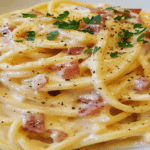 Sos carbonara cremos cu spaghetti, bucăți de bacon și piper negru, fotografiat în prim-plan