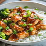 Pui teriyaki servit cu orez alb si broccoli, acoperit cu sos lucios si susan